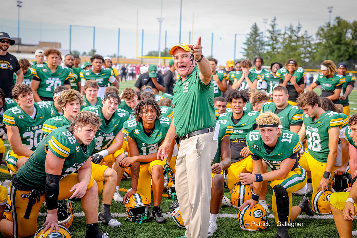 head coach tom lombardo with the varsity football team in a post-game huddle